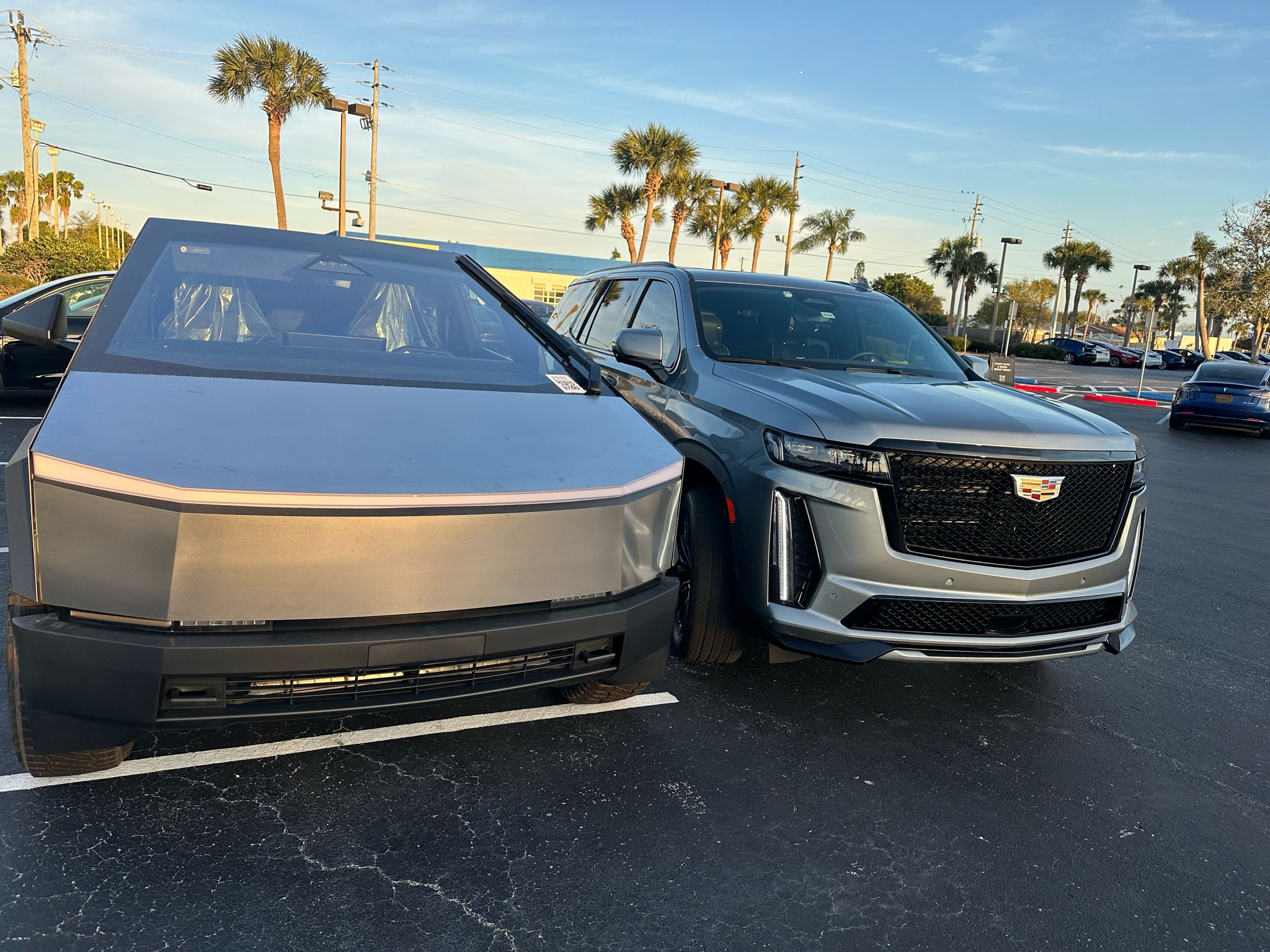 Two modern modes of transportation parked side by side: a silver electric pickup truck on the left and a gray luxury SUV on the right, ready for airport transfer.